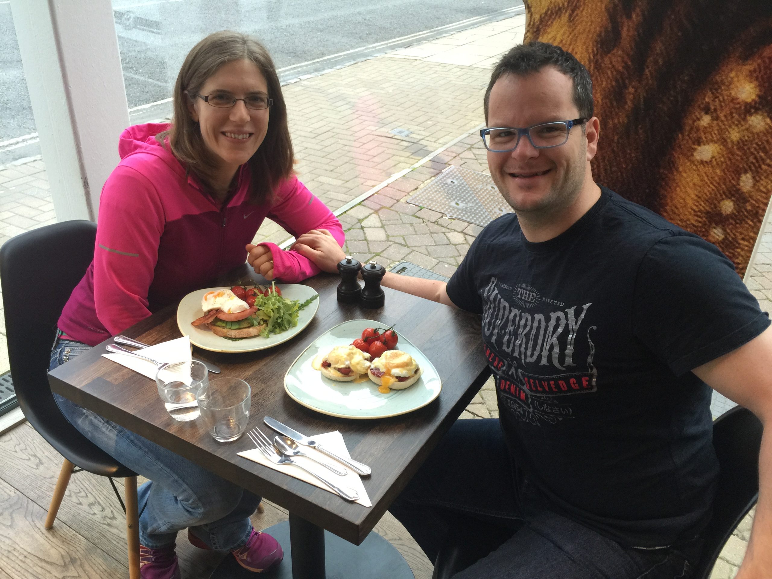 Katie Donegan and Alan Donegan enjoying a birthday breakfast at a caf&eacute; table with plates of food, including eggs benedict and delicious breakfast, marking a moment from 10 years ago.